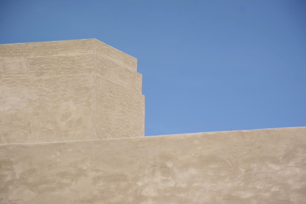 Sunlit sandstone architecture against clear sky — architectural texture for a travel mood board