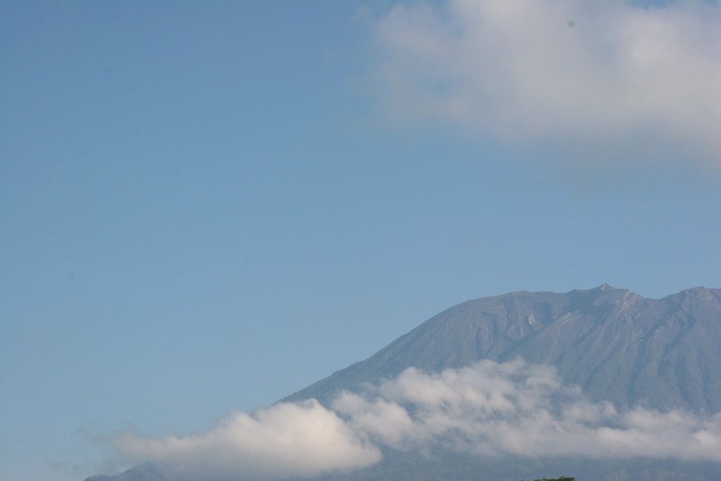Volcanic peak above a line of cloud — remote Africa and South America journeys from Australia